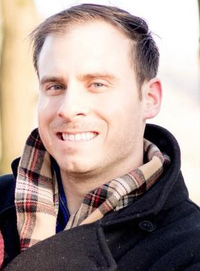 A tight close-up of Thomas Sittmann's face. He is wearing a dark colored wool coat and plaid scarf.